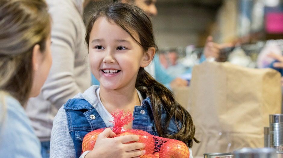 Stock photo of a little girl donating food during a food drive