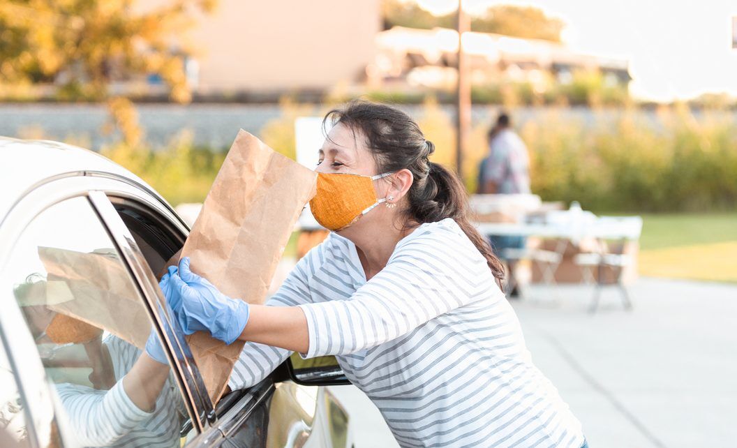Volunteer hands out food at drive through food bank