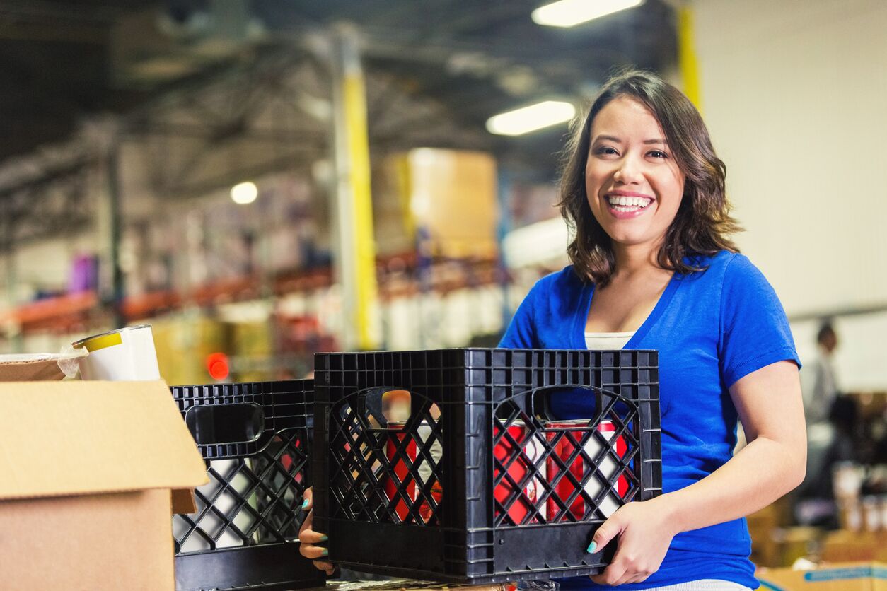A young female volunteer working in food bank warehouse